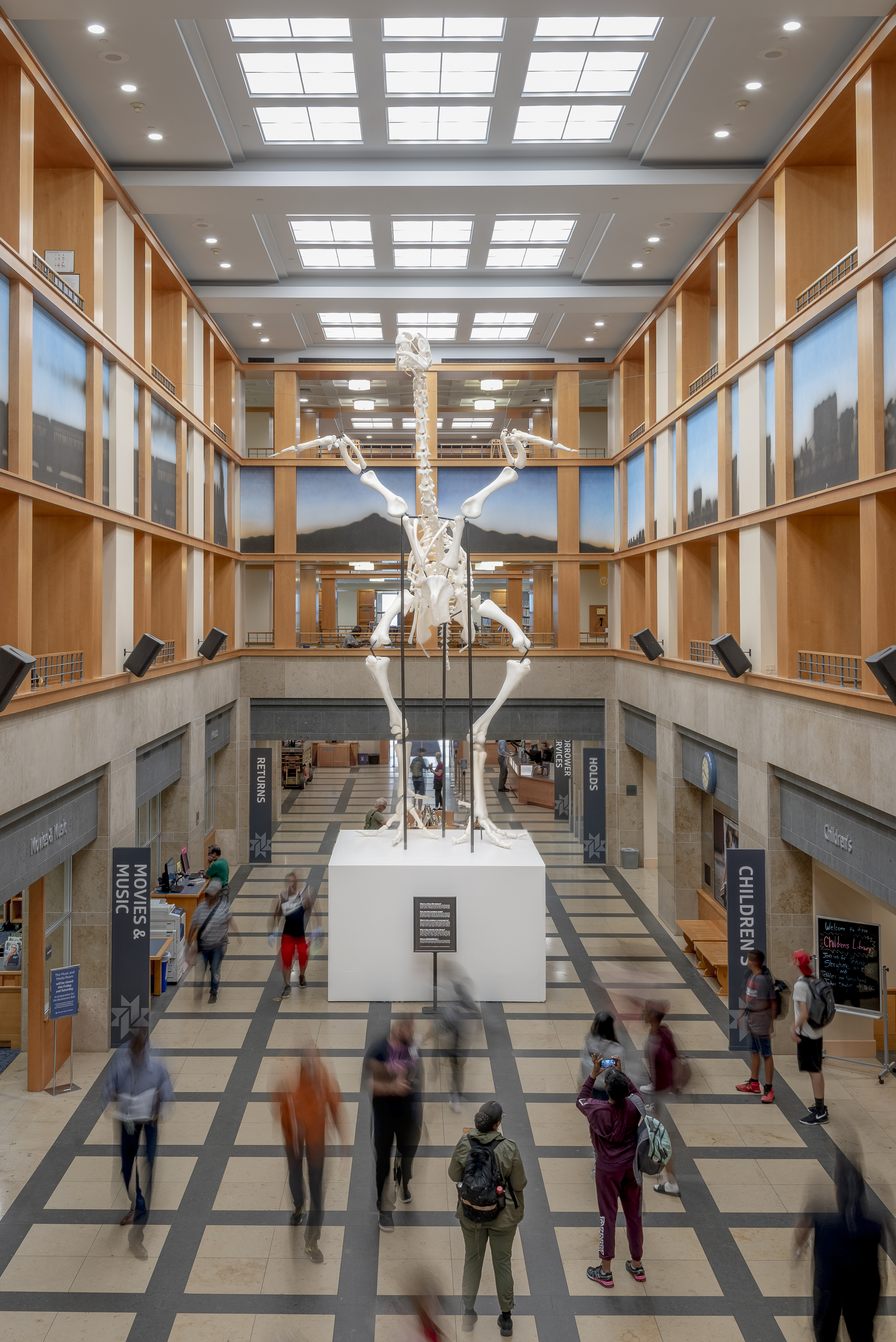 A large sculpture of a chicken skeleton fills the atrium of a library.